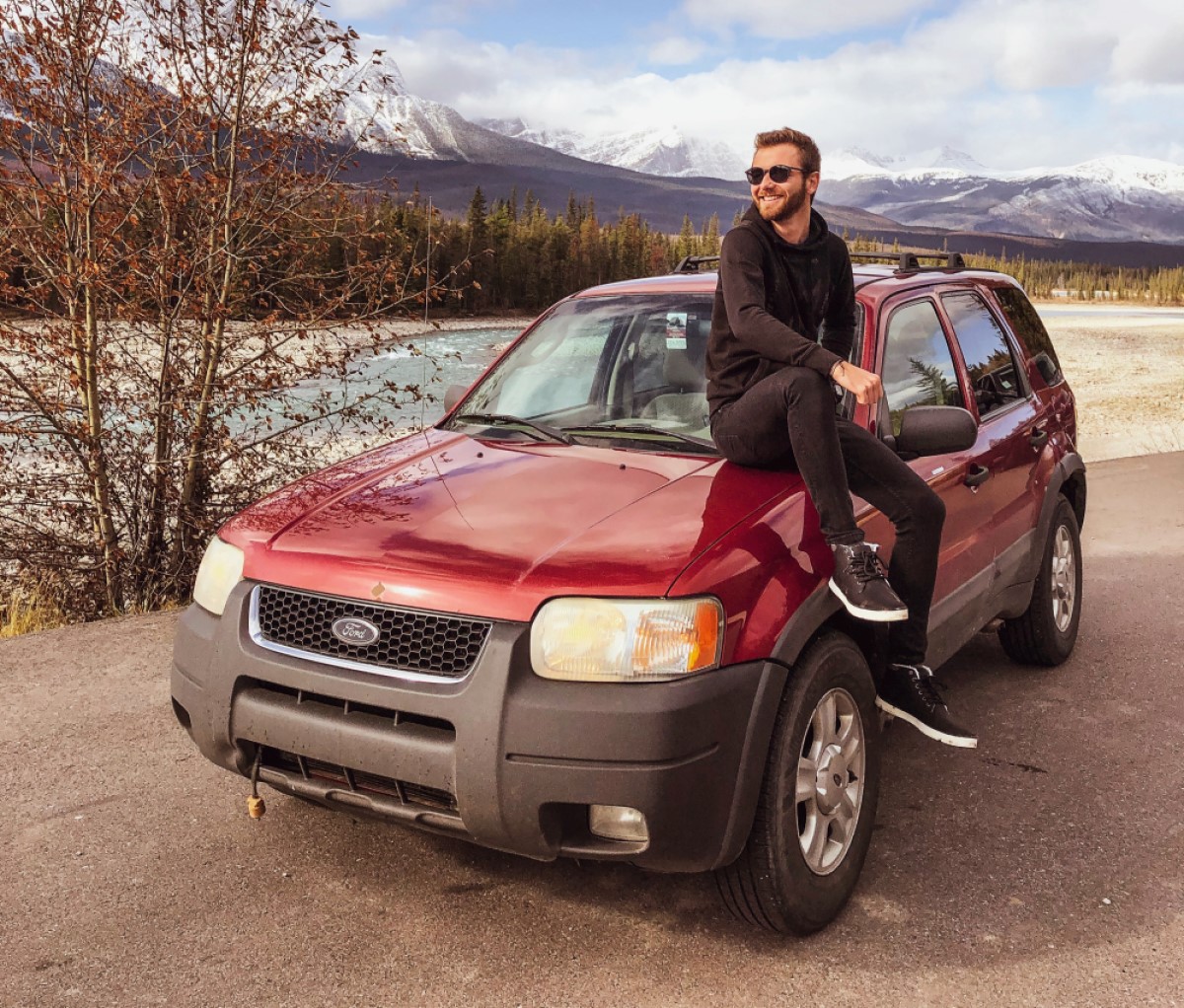 Kluk sedí na autě v kanadské přírodě
