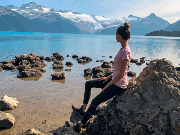 Dívka opřená o kámen s výhledem na hory v Kanadě